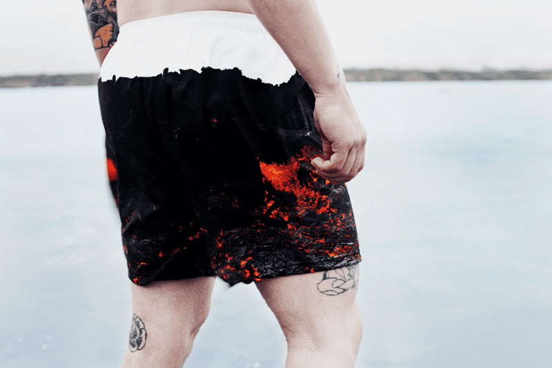 Man wearing Secret of Iceland swim trunks decorated with a volcanic lava design.